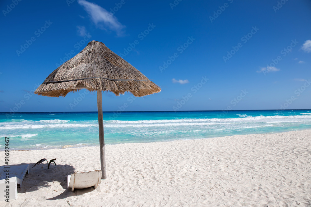 Caribbean sea coastline with grass sun umbrella and wooden beach
