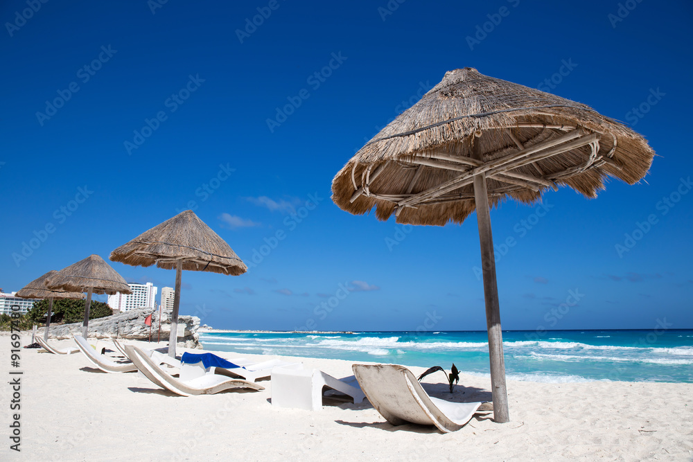 Caribbean sea coastline with grass sun umbrellas and wooden beac