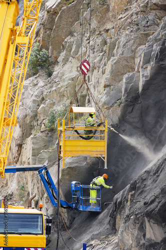 buider worker in crane vehicle sprayed concrete shotcrete in highway slope for prevent collapse photo