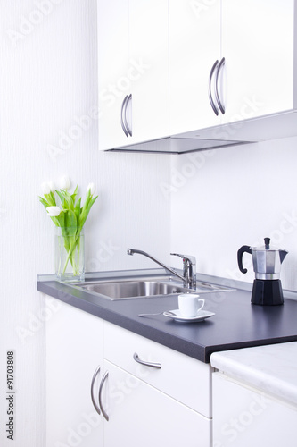 Percolator and cup of coffee on worktop, kitchen interior