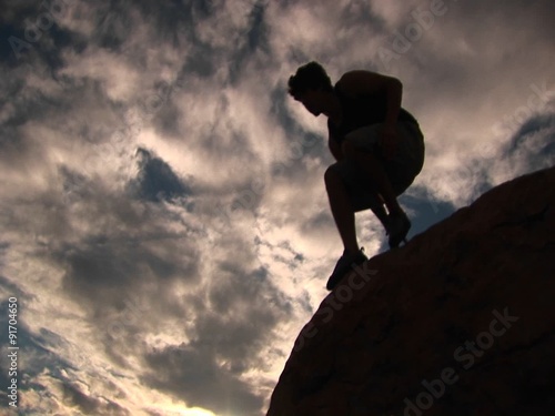 Wallpaper Mural Low-angle of a silhouetted hiker in the Santa Barbara Mountains hopping from boulder to boulder. Torontodigital.ca
