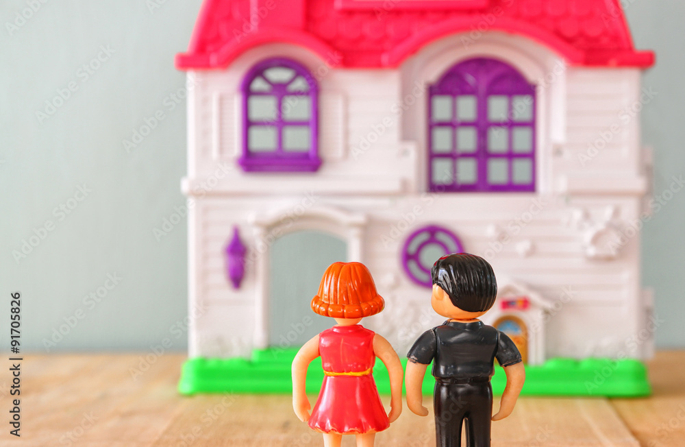 Naklejka premium concept image of young couple in front of new house. little plastic toy dolls (male and female) , selective focus. 