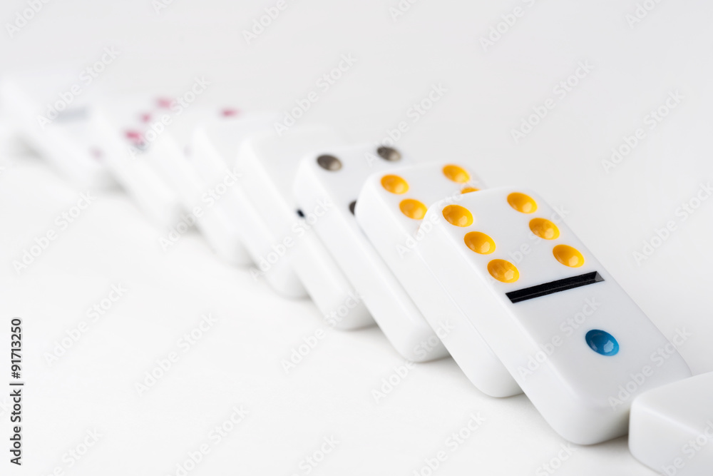 The domino effect of white blocks, with colorful numbers. Selective focus on the front part of the domino blocks. White Background. The domino effect of white blocks, with colorful numbers. Selective focus on the front part of the domino blocks. White Background.