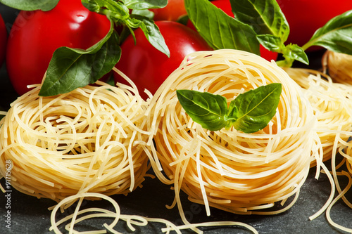 Dry Italian pasta fidellini with basil and tomato, selective foc