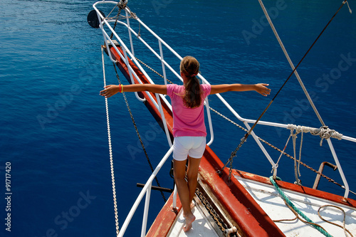 Young girl on the boat with arms in an imaginary flight