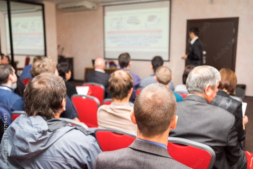 students sitting in a lecture room with teacher in front of the class with white projector slide screen