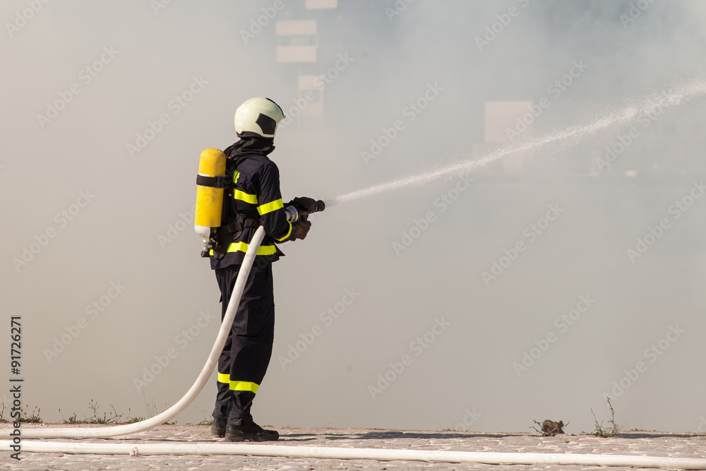 Firefighter in protective suit works with water hose. Fighting for a fire attack Firefighter in protective suit works with water hose. Fighting for a fire attack