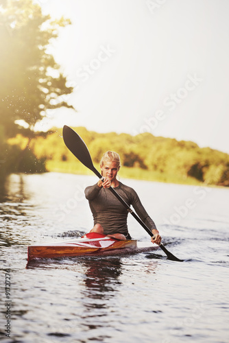 Athletic young woman paddling on lake in summer