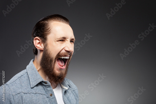 Cheerful young man with beard is expressing anger © Yakobchuk Olena