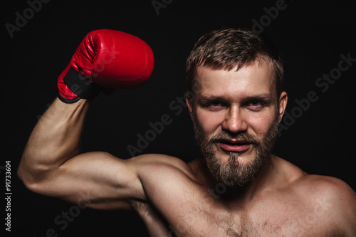 Athletic bearded boxer with gloves on a dark background