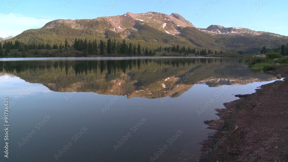 The Rocky Mountains are perfectly reflected in an alpine lake. The Rocky Mountains are perfectly reflected in an alpine lake.
