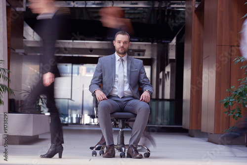 business man sitting in office chair, people group  passing by © .shock