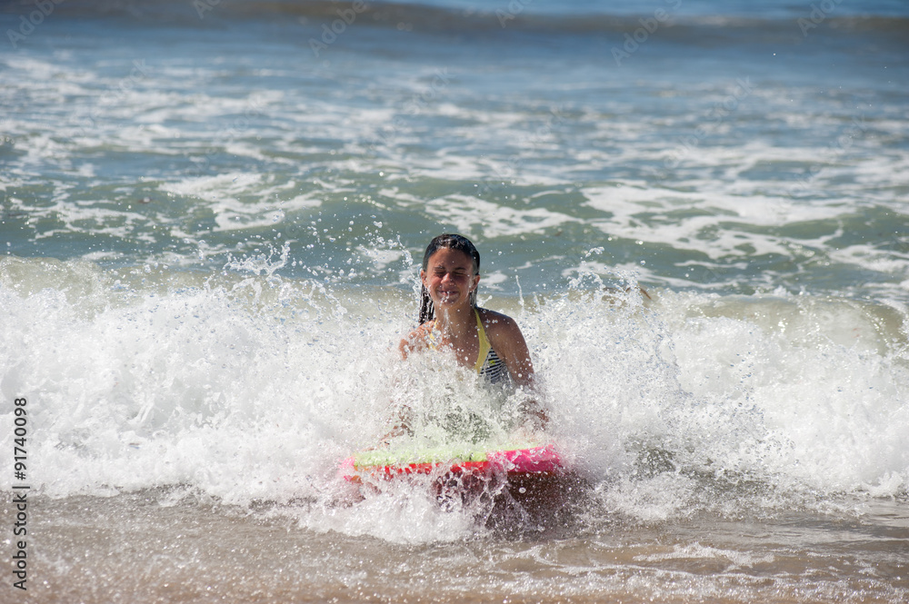 Girl child getting splashed in the face as she rides the boogie board. Girl child getting splashed in the face as she rides the boogie board.