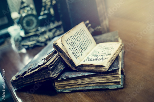 Antique books with old cyrillic text lying on a table in a dark library room. Education and learning concept. 