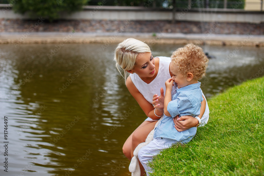 Fototapeta premium Blond female relaxing with her child in a park.