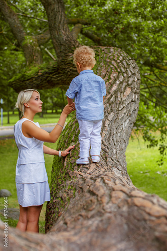 Mom and her child playing on big tree. © Fxquadro