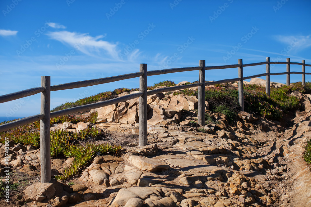 stone path with a fence on the edge of the cliff