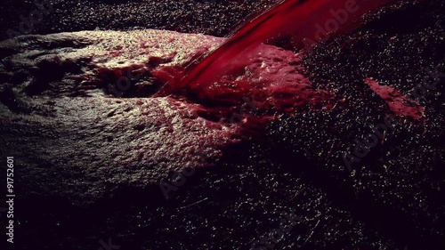 Production footage of red wine being poured into wine vat with winemaker testing and tasting red wine in winery cellar after vintage and harvest. 