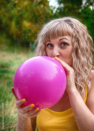 beautiful woman is blowing up a balloon