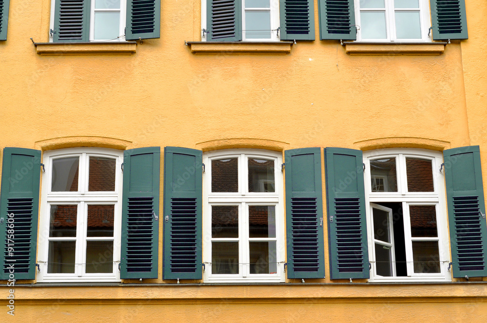 Windows with shutters on yellow wall 