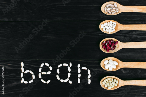 A colorful of beans in wood spoon on wood background