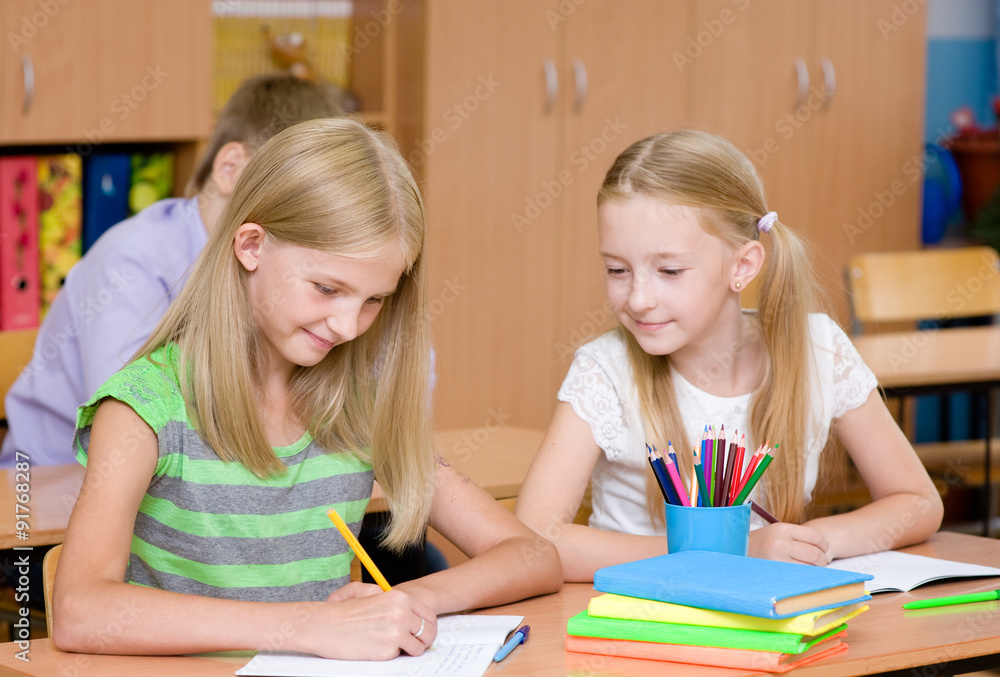 Schoolgirl cheating at exam, looking at a friend's writing Schoolgirl cheating at exam, looking at a friend's writing