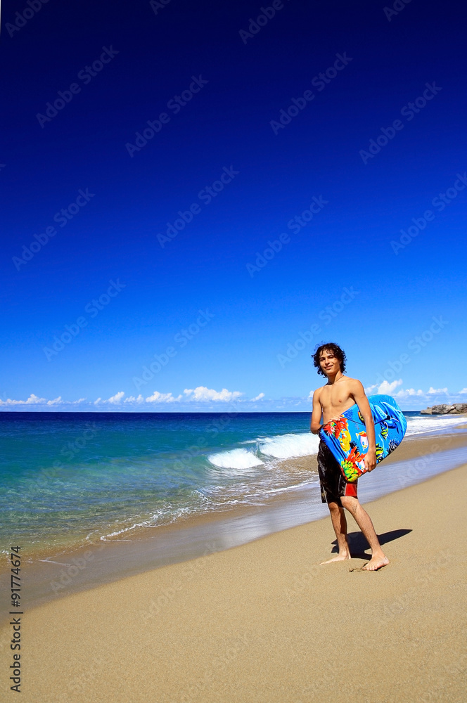Surfer holding a surf board on tropical beach Surfer holding a surf board on tropical beach