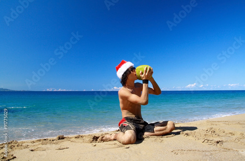 Santa Claus with green coconut fruit on beach of ocean