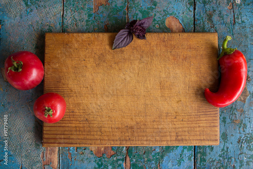 rustic vegetable frame for text from the cutting board, basil, tomato and pepper photo