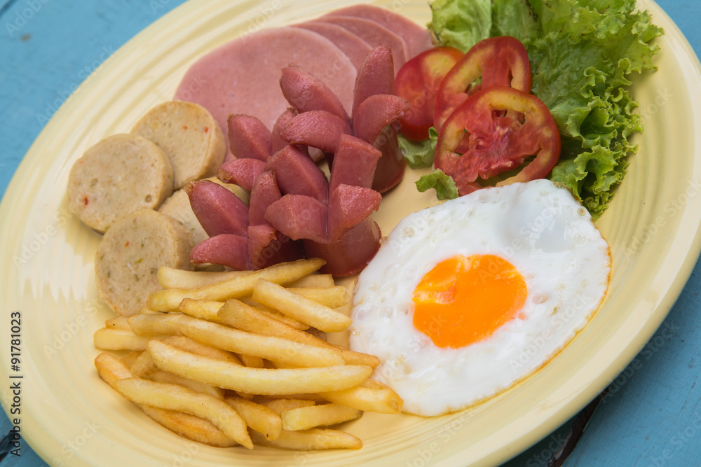 Breakfast with fried eggs, bacon, sausages,french fries
