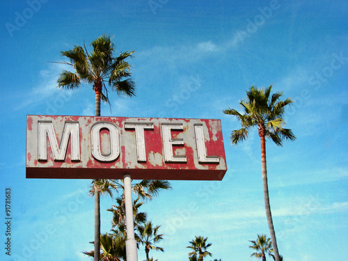 aged and worn vintage photo of motel sign with palm trees