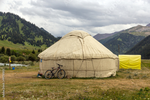 Yurt in Central Asian Veld Traditional Mongol Nomad Housing assembled on Green Meadow among High Mountain Hills in Kyrgyzstan and a Bicycle lean on it