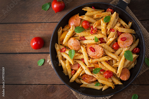 Penne pasta with tomatoes and sausage. Top view