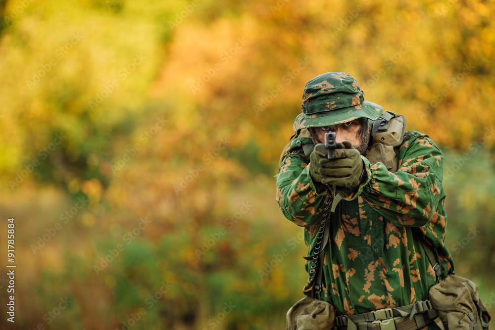 Fototapeta premium young soldier aiming and shooting with a pistol