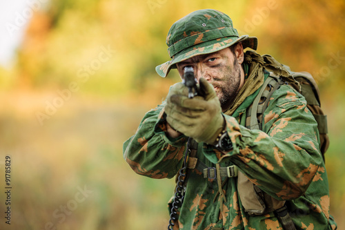 young soldier aiming and shooting with a pistol