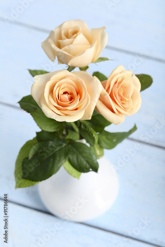 Bouquet of orange roses in vase on blue wooden background
