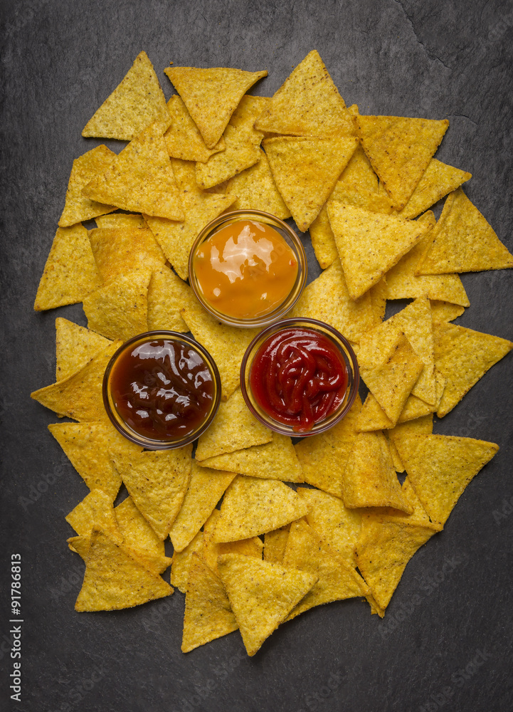 Mexican nachos with three different sauces on rustic wooden background close up top view Mexican nachos with three different sauces on rustic wooden background close up top view