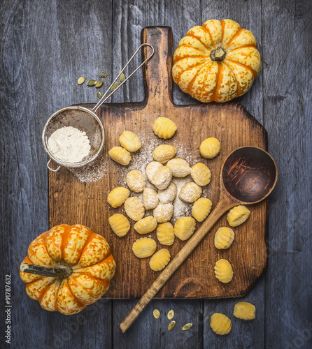pumpkin gnocchi  with flour pumpkins spoon on a wooden cutting board on dark rustic background   top view