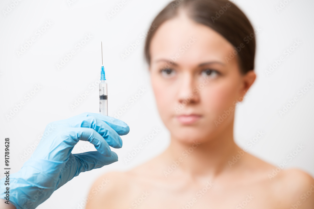 Hand with syringe on a background of a young girl Hand with syringe on a background of a young girl