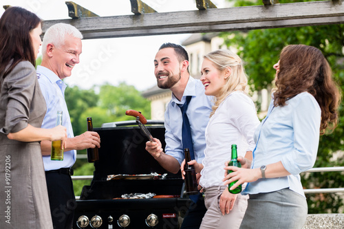 Team von Kollegen beim Grillen nach Feierabend mit Bier und Würstchen photo