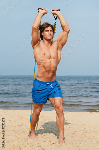 Guy working out with rubber band on the beach