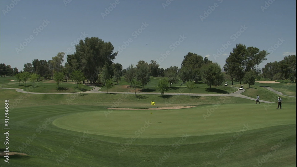 Pan to green as golfers walk onto green Pan to green as golfers walk onto green