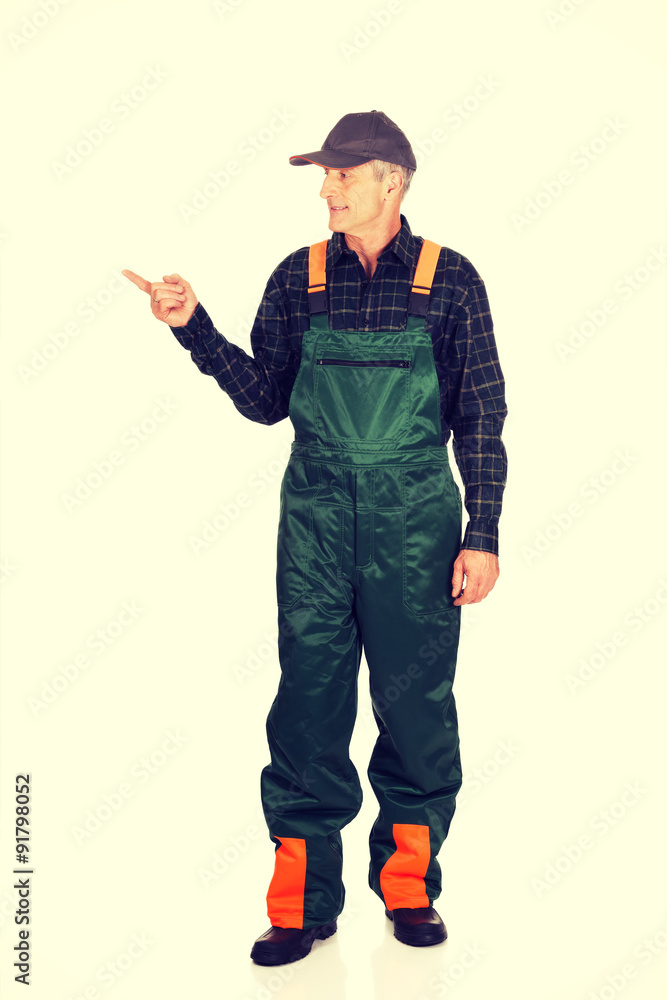 Mature gardener in uniform pointing to the left Mature gardener in uniform pointing to the left