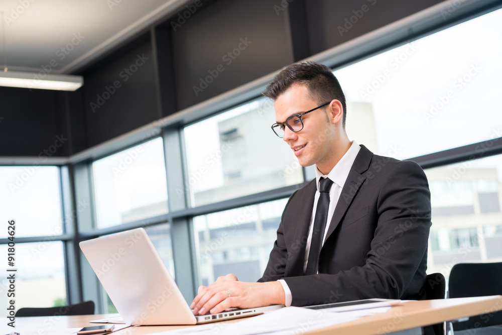 Young businessman in shirt and tie working on laptop at the offi Young businessman in shirt and tie working on laptop at the offi
