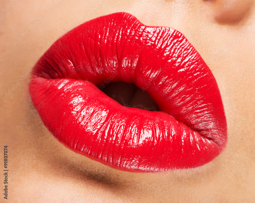Fototapeta premium Woman's lips with red lipstick and kiss gesture