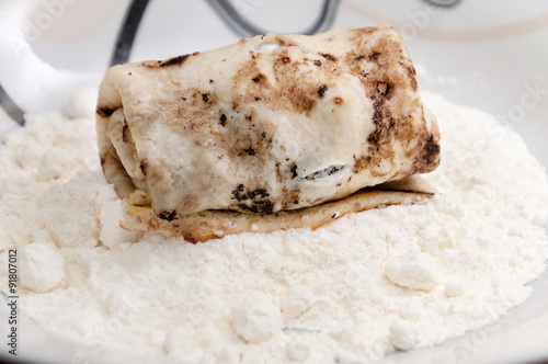 Stuffed rolled pancake in the flour ready for paning