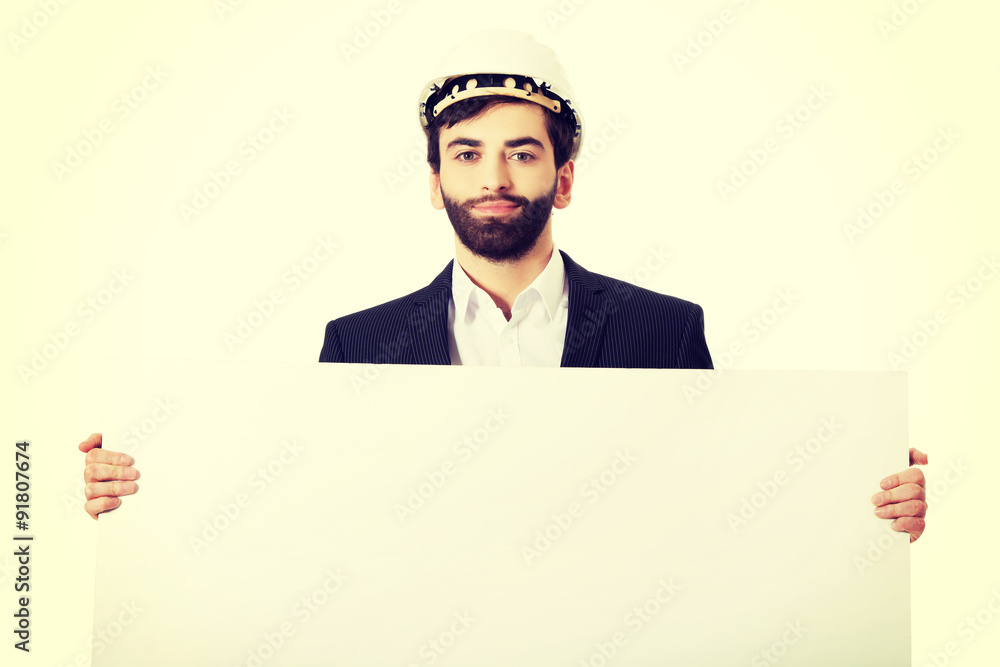 Handsome engineer in helmet holding empty banner. Handsome engineer in helmet holding empty banner.
