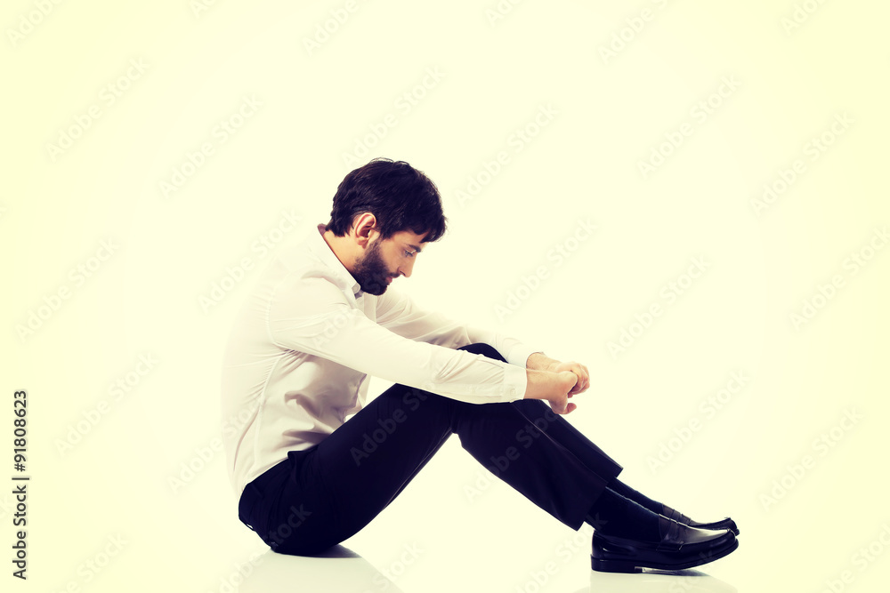 Young businessman sitting on the floor. 