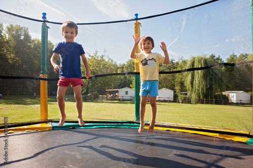 Two sweet kids, brothers, jumping on a trampoline, summertime, h photo