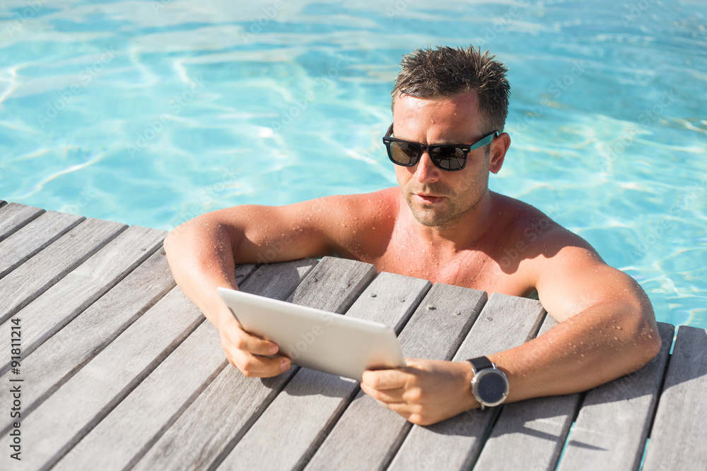 Man with digital tablet computer by the pool Man with digital tablet computer by the pool